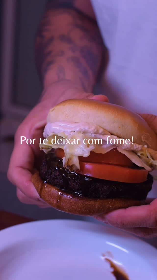 Burger vegano do Las Chicas servido nas mãos: pão brioche, tomate, molho escuro e maionese cremosa