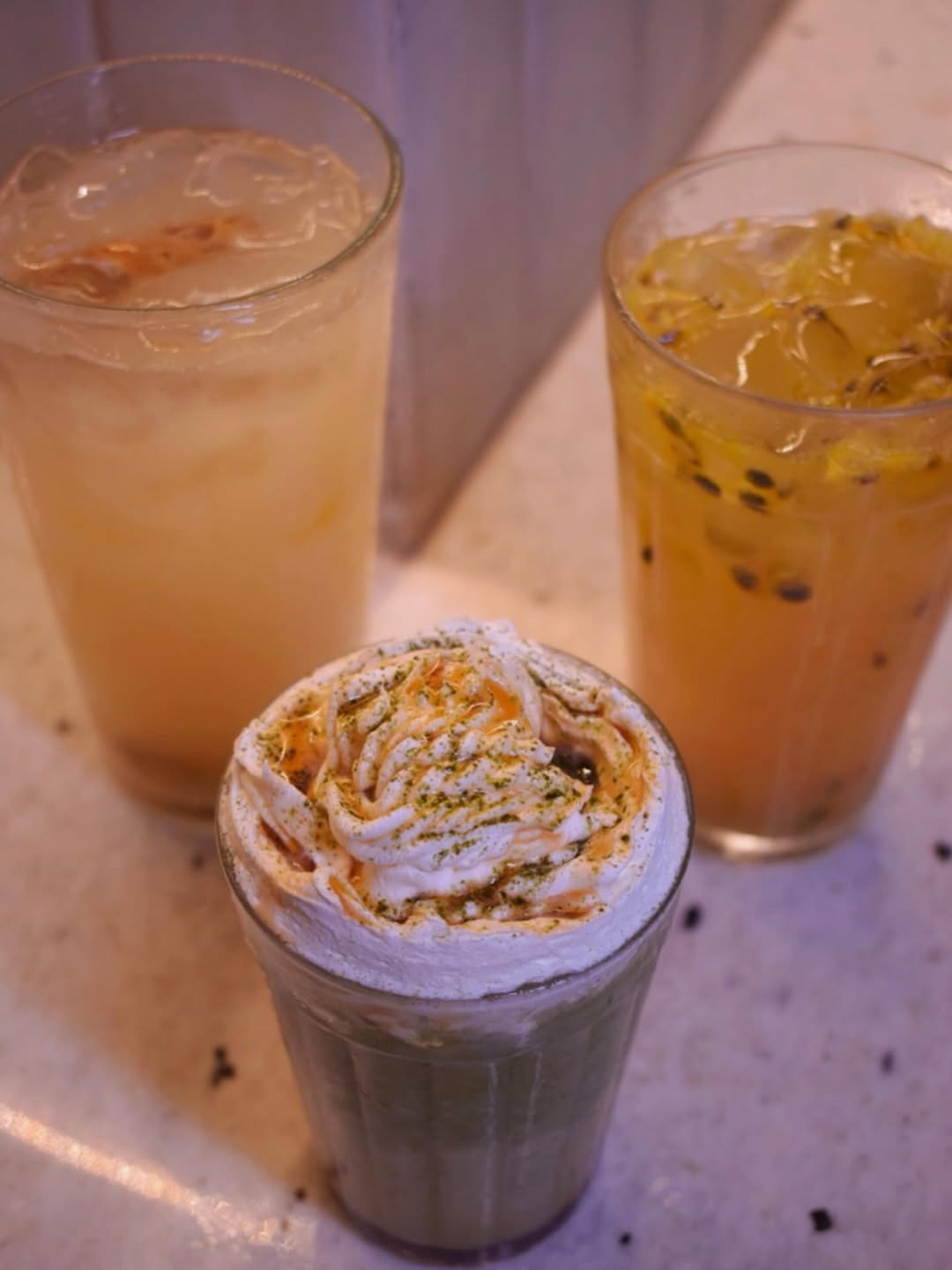 Três drinks do Las Chicas Vegan: um cremoso com chantilly e caramelo, um de maracujá com sementes e um claro com gelo
